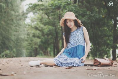 Portrait of smiling young woman sitting against trees