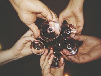 Cropped hands of friends toasting wineglasses at night