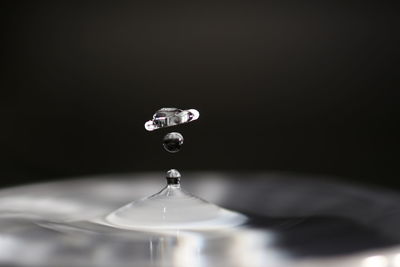 Close-up of drop falling on water against black background