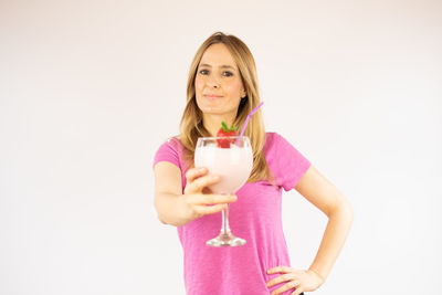 Portrait of a beautiful young woman drinking glass against white background