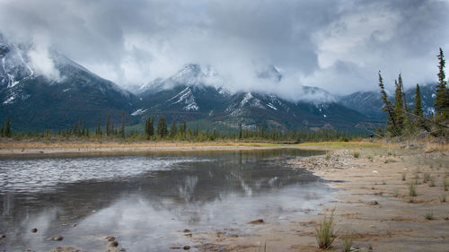 Scenic view of lake by mountains against sky