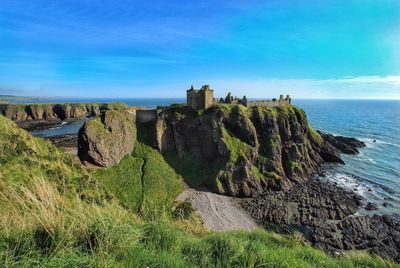 Castle on mountain by sea against blue sky