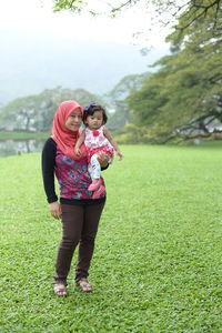 Mother with daughter standing on grass