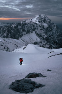 Person on snowcapped mountain against sky