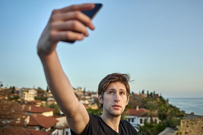 Portrait of man using smart phone against sky