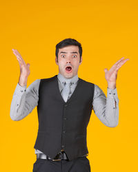Portrait of young man standing against yellow background
