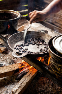 Close up of hand roasting cocoa bean on frying pan