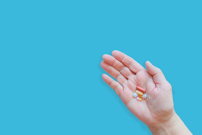 Close-up of woman hand against blue background