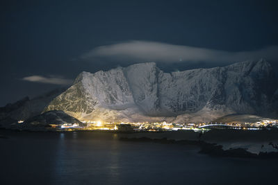 Illuminated snowcapped mountains against sky at night during winter