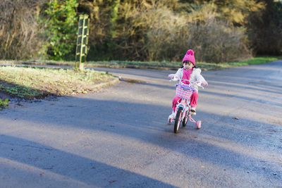 Girl wearing knit hat riding bicycle on road