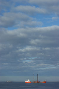 Boat sailing in sea against cloudy sky
