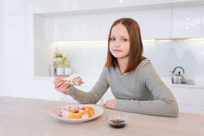 Portrait of young woman sitting on table at home