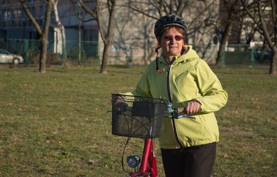 Portrait of woman with bicycle standing on field