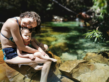 Mother and daughter cooling off in summer at waterfall.