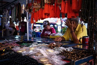 Man buying bead necklaces at market stall