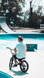 Rear view of man riding bicycle in swimming pool