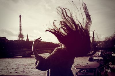 Woman with tousled hair at seine river against eiffel tower