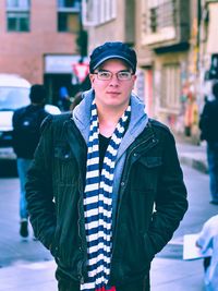 Portrait of young man standing on street in city