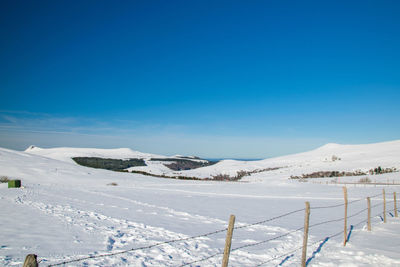 Scenic view of snow covered mountains against blue sky