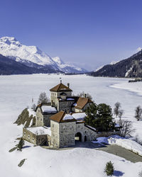 Buildings by mountains against sky during winter