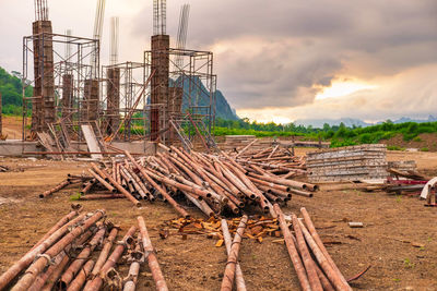 Stack of logs on field against sky