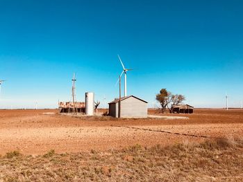 Windmill on field against clear blue sky