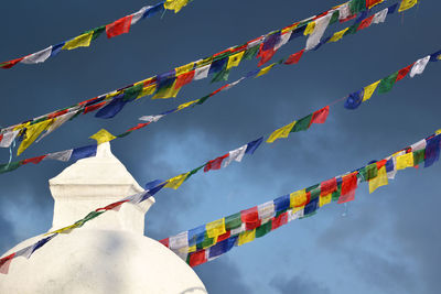 Boudhanath stupa and buddhist prayer flags against cloudy blue sky, kathmandu, nepal