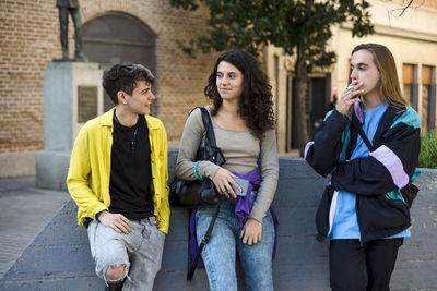 Friends talking while standing outdoors on the street.