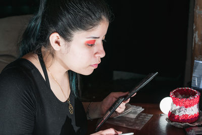 Beautiful latina woman with green hair, in front of her dressing table making up her eyes