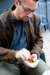 Close-up of man having food while sitting on chair outdoors