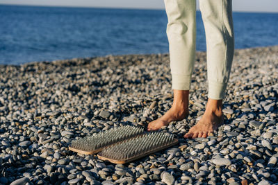 A woman prepares to stand on a sadhu board with nails for practice on the seashore.