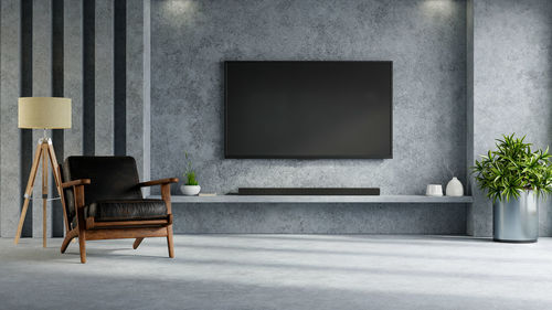 Concrete wall mounted tv on cabinet in living room with leather armchair and decoration minimal.