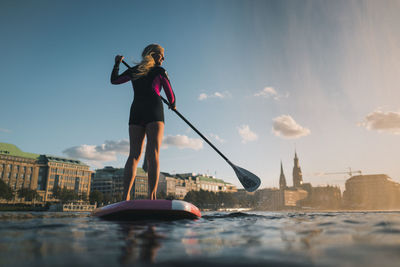 Woman standing on boat in city against sky