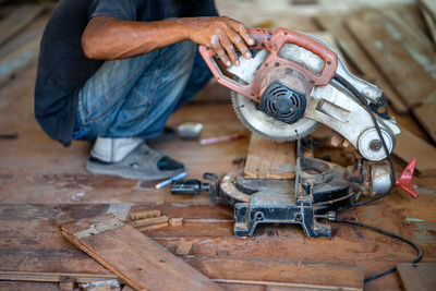 Low section of man holding electric saw in workshop