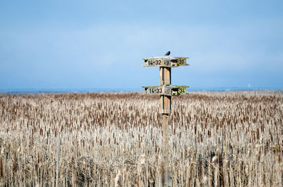 Information sign on field in front of plants against sky