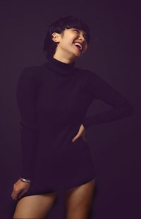 Smiling young woman standing against gray background