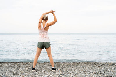 Full length of woman standing on beach against sea