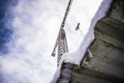 Low angle view of crane against cloudy sky