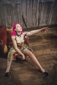 High angle view of female model looking up while sitting at chair on hardwood floor