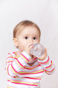 Portrait of cute boy drinking against white background