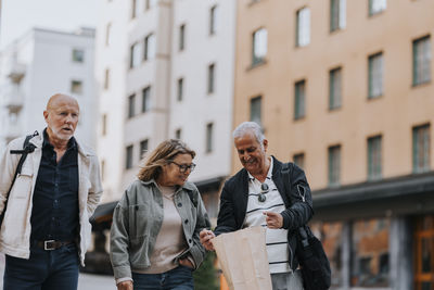 Smiling senior man showing shopping bag to elderly female friend