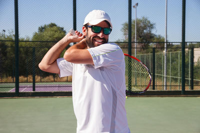 Smiling man playing tennis in court