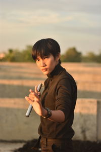 Portrait of young man holding nunchaku standing outdoors