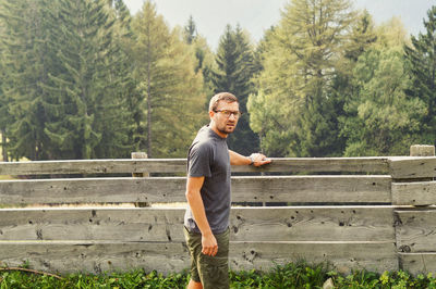 Portrait of contemplating man standing against wooden fence