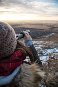 Rear view of woman looking through binoculars against sky