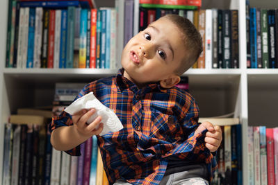 Portrait of boy holding book at home