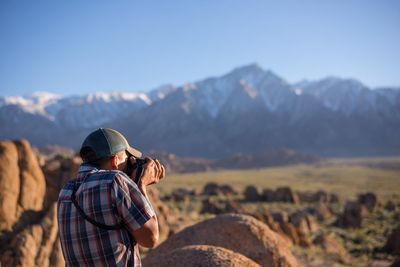 Rear view of woman standing on mountain against sky