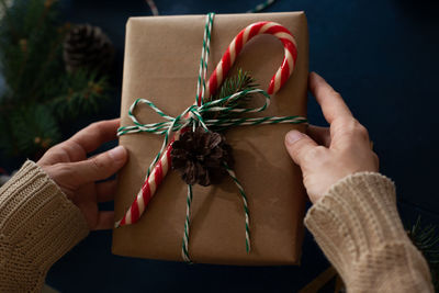 Woman wraps a handmade eco style christmas present in kraft paper and natural spruce branches 