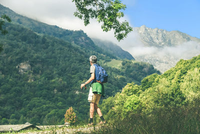 Man walking in mountain forest. male with backpack do hike in the nature. guy goes trekking outdoor