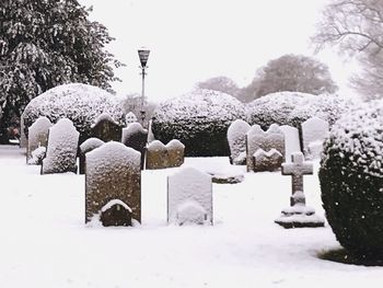 People in cemetery against sky during winter